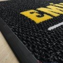 Siyah zeminli sarı logolu paspas P5012