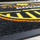 siyah zeminli sarı turuncu logolu paspas P5086